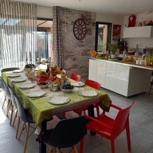 a table in a kitchen with red chairs and a table sidx sidx sidx at A L'OMBRE DES 2 TILLEULS maison d'hôtes adults only in Sainte-Pazanne