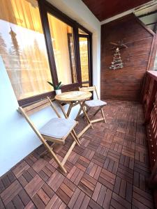 eine Terrasse mit 2 Stühlen, einem Tisch und einem Fenster in der Unterkunft Studio Enis in Poiana Brașov