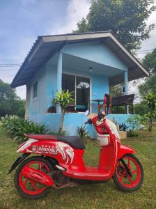 a red scooter parked in front of a blue house at Miss You Beach Resort Koh Mak in Ko Mak