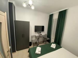 a bedroom with a bed and a desk and a television at A Hotel Bishkek in Bishkek