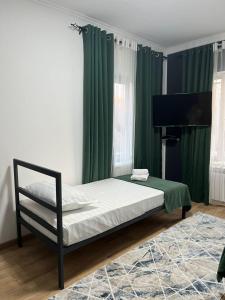 - une chambre avec un lit doté de rideaux verts et d'un piano dans l'établissement A Hotel Bishkek, à Bishkek