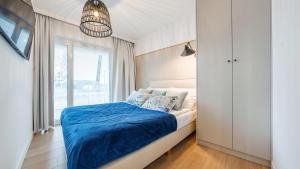 1 dormitorio con cama con sábanas azules y ventana en Apartament Lux Tukan B002, Polanki Aqua - Holiday City en Kołobrzeg