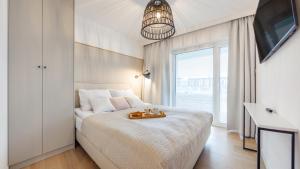 a white bedroom with a bed with a tray on it at Apartament Lux Tukan B002, Polanki Aqua - Holiday City in Kołobrzeg