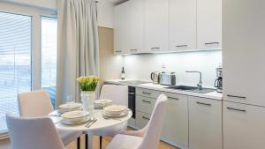 een witte keuken met een witte tafel en stoelen bij Apartament Lux Tukan B002, Polanki Aqua - Holiday City in Kołobrzeg