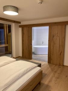 um quarto com uma cama e uma banheira em das MARX - Gasthof Marx - Apartments em Grosskirchheim