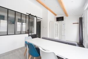 a dining room with a white table and blue chairs at L'Émeraude in Malesherbes