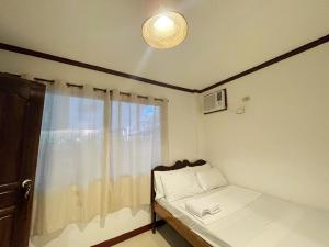 a small bedroom with a bed and a window at Lara's Guesthouse Siargao in General Luna