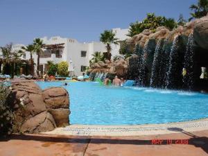 a swimming pool with a waterfall in a resort at لدينا مكتب عقارات في قرية دلتا شرم We have a real estate office in Delta Sharm in Sharm El Sheikh