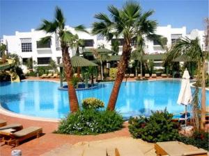 a large swimming pool with palm trees in a resort at لدينا مكتب عقارات في قرية دلتا شرم We have a real estate office in Delta Sharm in Sharm El Sheikh