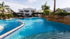 a large pool with blue water in a resort at لدينا مكتب عقارات في قرية دلتا شرم We have a real estate office in Delta Sharm in Sharm El Sheikh