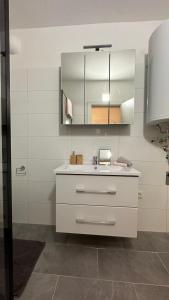 een witte badkamer met een wastafel en een spiegel bij Gemütliche Seeblickwohnung Lara in Sattendorf