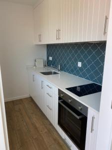 a kitchen with white cabinets and a black stove top oven at Quinta do ribeiro - refugio romântico com piscina panorâmica junto ao Geres in Arcos de Valdevez