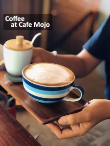 una persona che tiene una tazza di caffè al Cafe moto di The Reef Hotel & Studios a Koh Lipe