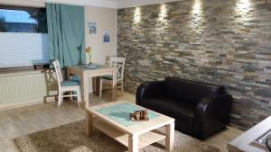 a living room with a black leather couch and a brick wall at Appartement Ursula Eck in Bergisch Gladbach