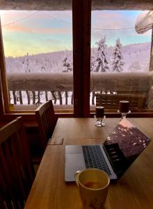 un tavolo con un computer portatile e una tazza di caffè sopra di Ruka View at the Slopes Ski in, Family & Bike Park, National Park, hike trails - Lapland Villas a Ruka