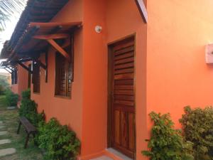 un edificio naranja con una puerta de madera y un banco en Chalés Farol Village, en Fortim