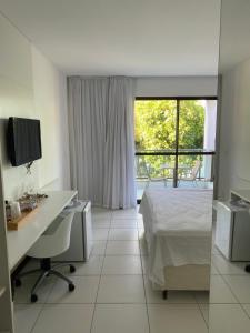 Schlafzimmer mit einem Bett, einem Schreibtisch und einem Fenster in der Unterkunft Iloa Resort in Barra de São Miguel