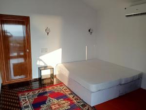 a bedroom with a bed and a window and a rug at Riya Cottages and Beach Huts in Agonda