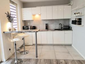 a kitchen with white cabinets and a counter with stools at Apartment DAISY, balcony, 5 os, Down Town in Kraków