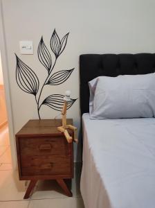um quarto com uma cama e uma mesa de cabeceira com uma planta na parede em Lindo apto vista lateral do mar Itararé São Vicente em São Vicente