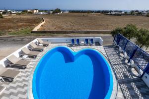 una gran piscina azul con sillas y un campo en Honeymoon Beach Studios, en Perivolos