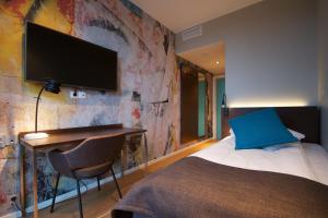 a bedroom with a bed and a desk with a tv on a wall at Comfort Hotel Victoria Florø in Florø