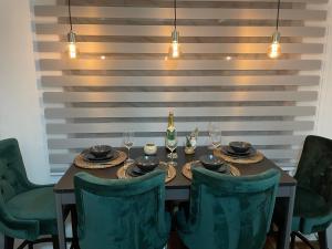 - une table avec des chaises vertes et une bouteille de vin dans l'établissement Luxury Sunny Hill, à Kopaonik