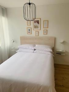 um quarto com uma grande cama branca e um lustre em SAN LORENZO HUESCA con parking em Huesca