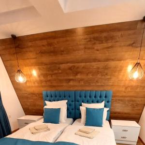 uma cama com uma cabeceira azul e duas luzes em Къща за гости Радост Guest House Radost em Razlog