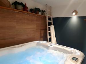 a bath tub with water in it in a bathroom at Le Bon Temps, pour une douce parenthèse in Saint-Martin-lez-Tatinghem