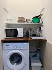a kitchen with a washing machine and a microwave at Appartamento Cenisia Fermata Racconigi in Turin