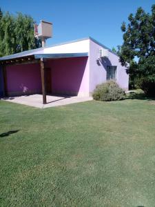 un edificio rosa y blanco con un patio de césped en Cabañas La Soñada en San Rafael