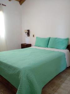 1 cama verde grande en una habitación blanca en Cabañas La Soñada en San Rafael