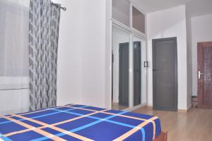 1 dormitorio con 1 cama azul en una habitación en RÉSIDENCE BELLEVUE SITO AIPORT- Lomé en Lomé