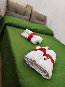 - un lit vert avec des serviettes dans l'établissement Santa Barbara Apartment, à Catane