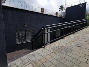 un edificio negro con una valla al lado de una acera en La escondida house, en Medellín