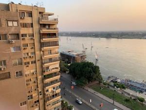 a tall building next to a river with boats in it at Schöne Wohnung mit Blick auf Nil und Pyramiden in Cairo