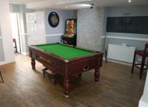 a room with a pool table and a clock on the wall at The Coastal Inn in Cellardyke