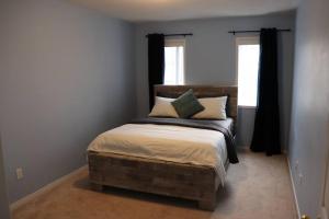 a bedroom with a bed with a wooden headboard and two windows at Entire 4 bed room detached residential home in Ajax