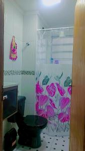 y baño con aseo y cortina de ducha. en Apartamento praia B, en Mongaguá
