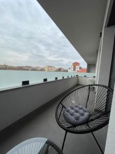 a chair on a balcony with a view of the water at Apartament Timisoara 6 in Timişoara