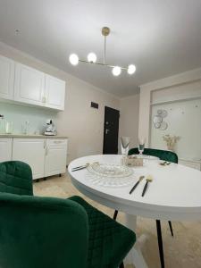 uma cozinha com uma mesa branca e cadeiras verdes em Apartament Timisoara 6 em Timisoara
