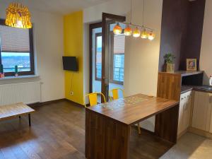 a kitchen with a wooden table and yellow chairs at Sunny Life Apartment in Warsaw