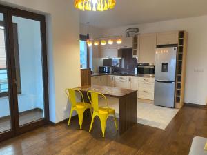 a kitchen with a wooden table and yellow chairs at Sunny Life Apartment in Warsaw