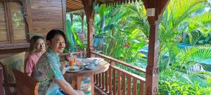 dos mujeres sentadas en una mesa en un porche en Galang hari villa, en Ubud
