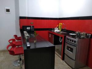 cocina roja y negra con fogones y fregadero en Departamento-Mamá Feli M5, en Chiclayo