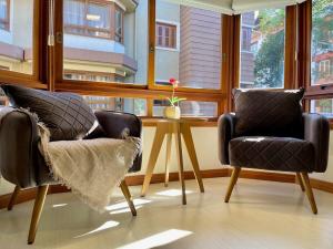 2 sillas y una mesa en una habitación con ventana en Apartamentos Condado Di Positano no CENTRO by Achei Gramado, en Gramado