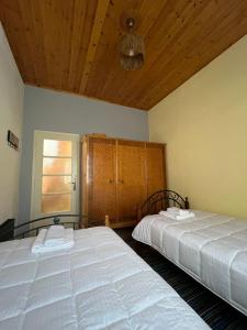 a bedroom with two beds and a wooden ceiling at Sweet home in Kalavrita +7 photos
