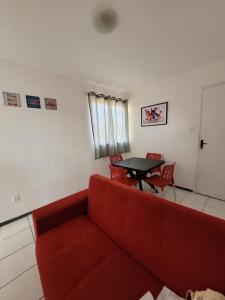 uma sala de estar com um sofá vermelho e uma mesa em Apartamento Tupy I - Turu em São Luís