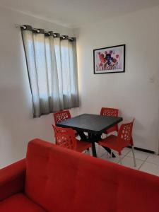 uma sala de estar com um sofá vermelho e uma mesa e cadeiras em Apartamento Tupy I - Turu em São Luís